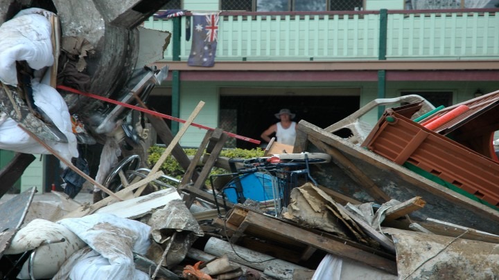 Man standing in front of his property after it was devastated by natural disaster